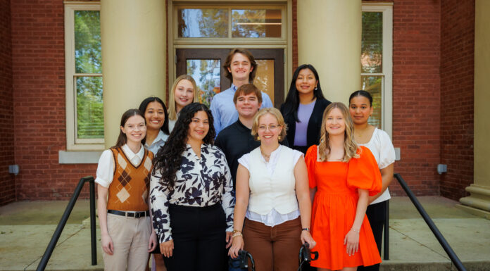 Office of Global Engagement awards 22 scholarships for students to study abroad Ten people pose and smile for a group photo on outdoor steps in front of a brick building with columns.