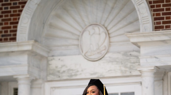 Graduate Spotlight: Addison Robinson Addison Robinson, in graduation attire, stands on steps in front of building, with two framed diplomas displayed on the ground.