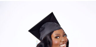 Artisha Wright, in a graduation cap and gown, smiles while posing against a plain white background.