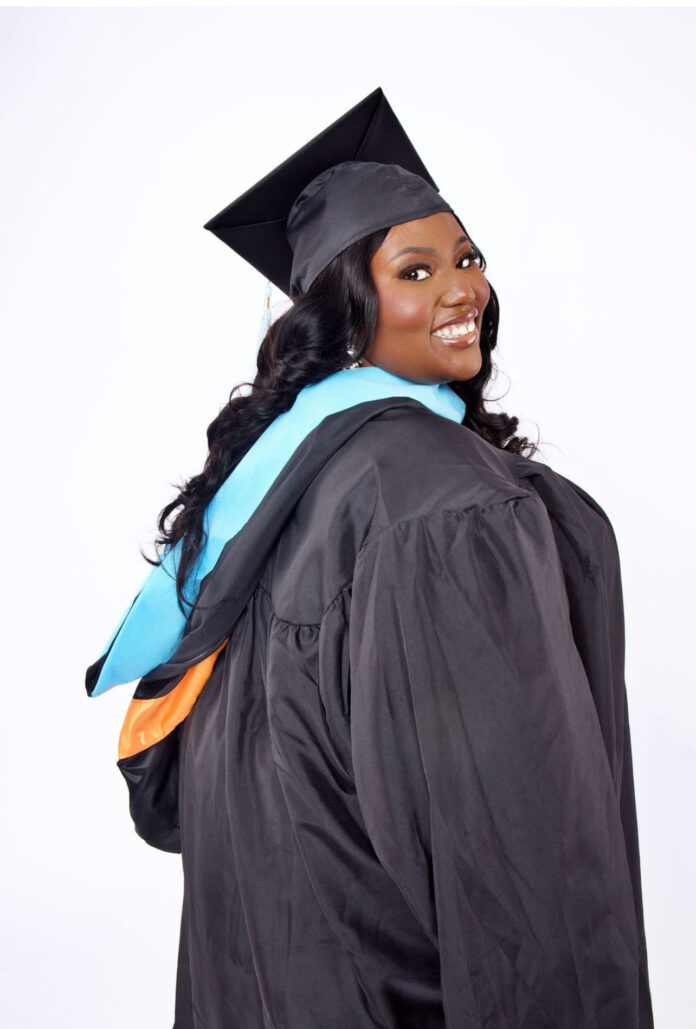 Artisha Wright, in a graduation cap and gown, smiles while posing against a plain white background.