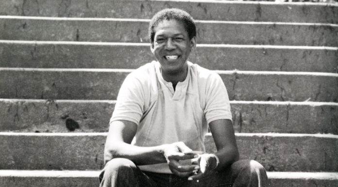 Dr. Bobby Jones lived to help and connect with others | Mercer Legends A man sits on outdoor concrete steps, smiling, wearing a light polo shirt and pants, with hands clasped in front.