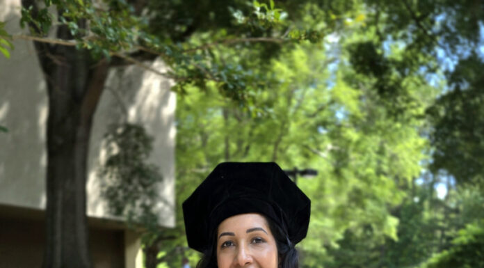 Graduate Spotlight: Deepthy Varghese Deepthy Varghese, in cap and gown, holds a bouquet of flowers and a plaque, standing outdoors on a sunny day.