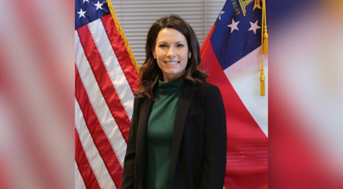 University appoints first female chief of police Woman standing in front of the American flag and the Georgia state flag, smiling at the camera.