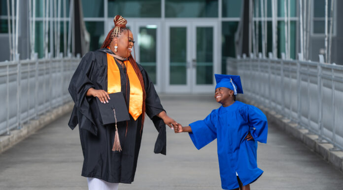 Graduate Spotlight: Kendra Johnson-Albritton Kendra Johnson-Albritton and a child in graduation attire hold hands and smile on a bridge outside a modern building.