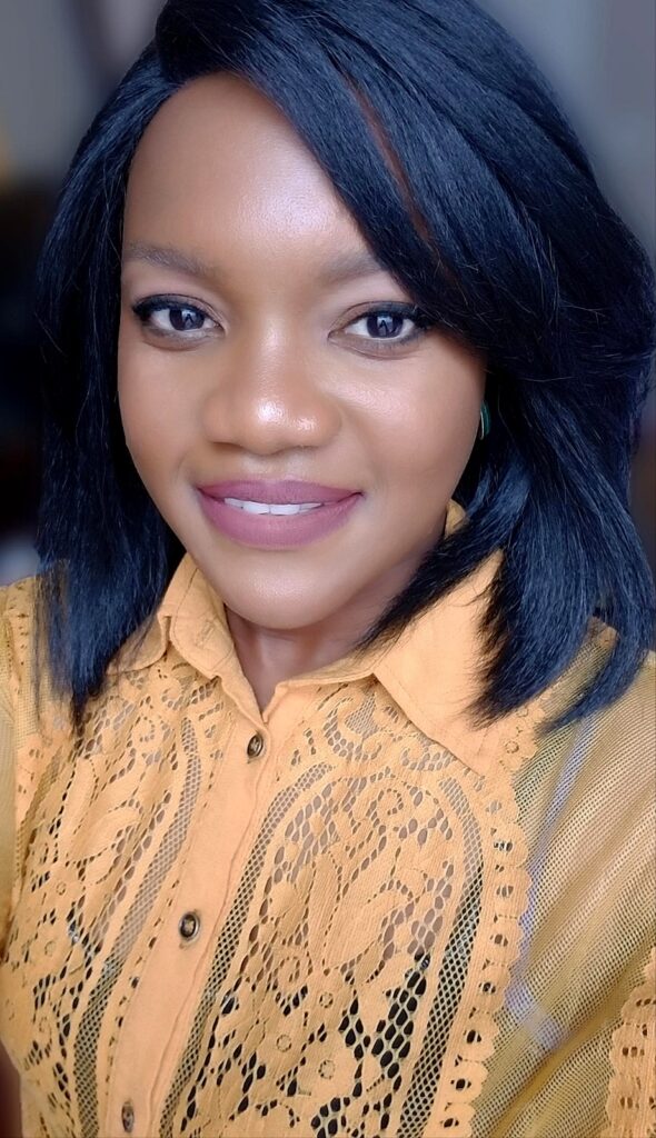 Woman with straight shoulder-length black hair wearing a yellow lace blouse, smiling at the camera.