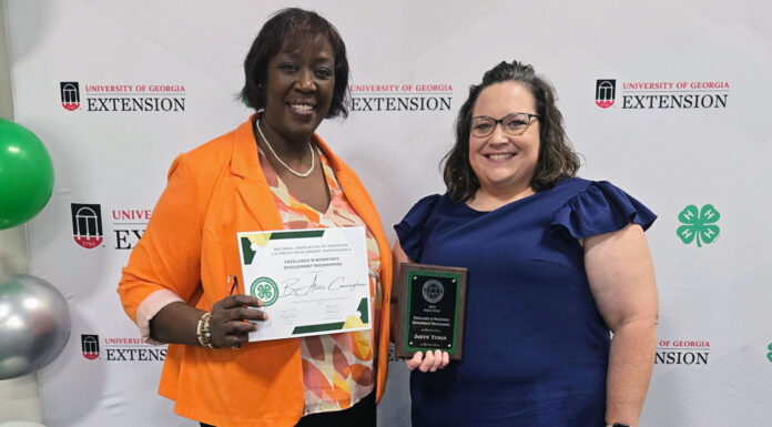 Mercer School of Medicine honored for excellence in workforce development Two women stand in front of a banner holding a certificate and a plaque.