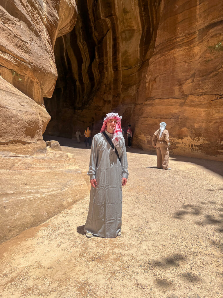 Henry Fraley, in traditional clothing, stands in a sunlit canyon, with others visible in the background.