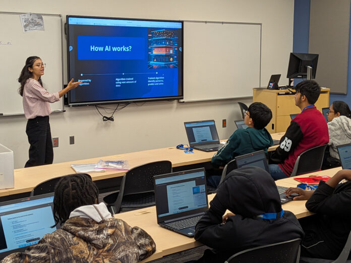murs-ai Kusum Neupane presents a slide titled How AI works? to students seated at desks with open laptops in a classroom.
