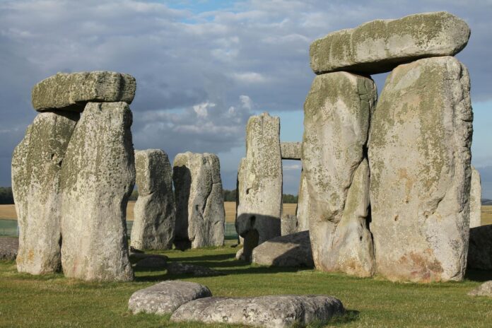 Large upright stone slabs with horizontal stones on top, forming part of the Stonehenge monument under a partly cloudy sky.