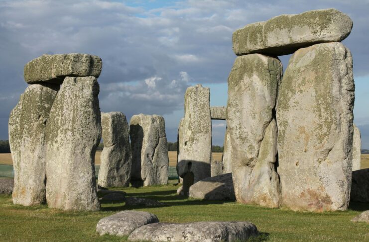 Large upright stone slabs with horizontal stones on top, forming part of the Stonehenge monument under a partly cloudy sky.