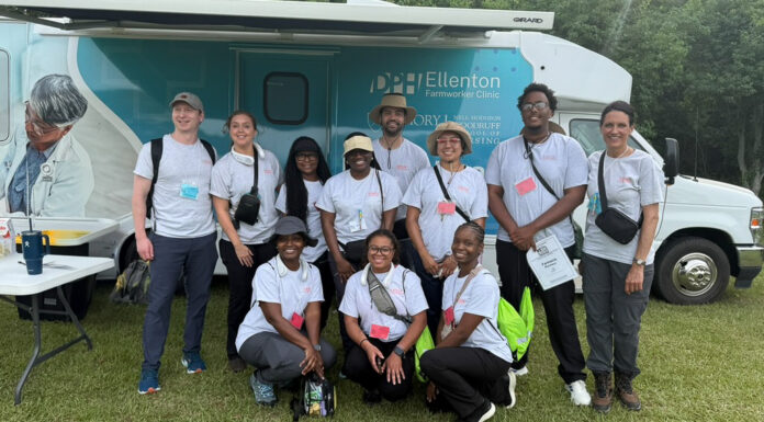 Pharmacy students help bring health care to farmworker families A group of people in matching shirts pose in front of a mobile health clinic parked on grass.