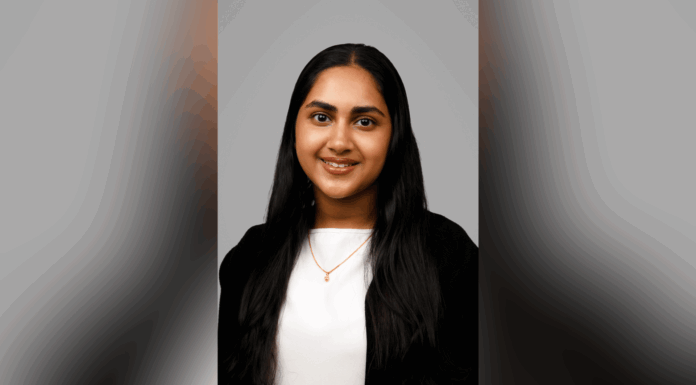 Mercerian selected for prestigious Fulbright Award A woman with long dark hair, wearing a white top, black cardigan, and a necklace, poses against a plain gray background.