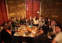 Mercer professors publish book about impact of study abroad on students A group of people sit around a low table, sharing a meal in a warmly lit restaurant with earthen walls.