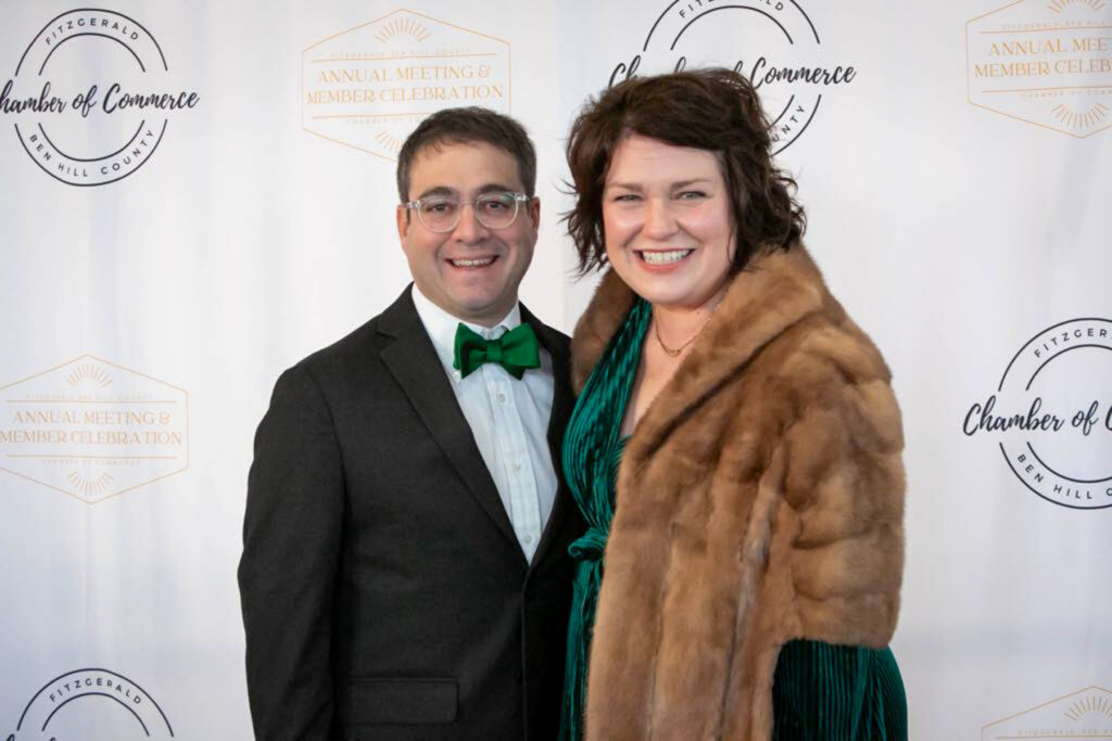Two people dressed formally pose in front of a step-and-repeat banner at a Fitzgerald-Ben Hill County Chamber of Commerce event.