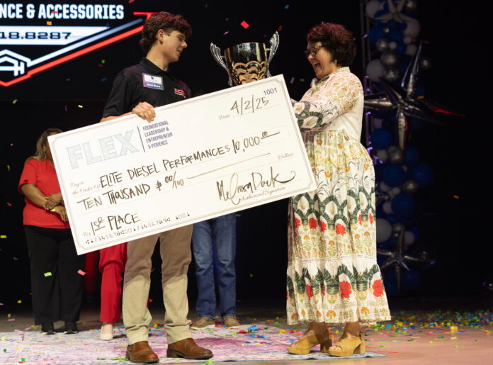 melissa-dark-3 A young man receives a trophy and a $10,000 check for first place at an event, standing beside a woman on stage.