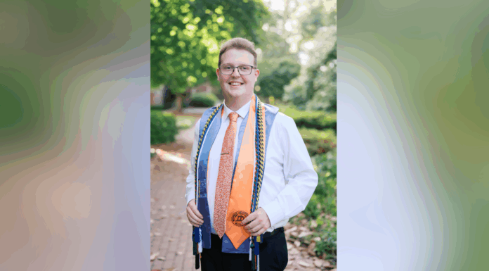 Recent graduate Carter Murdaugh named Phi Kappa Phi Fellow A young person in a white shirt and tie stands outdoors wearing graduation cords and a medal, smiling at the camera.