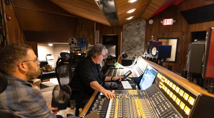 Mercer Music at Capricorn to offer Introduction to Studio Recording certificate Two men work at a large audio mixing console in a recording studio with wood-paneled walls and various audio equipment.