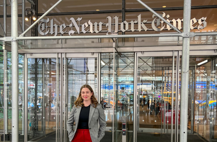 Rylee Kirk stands in front of The New York Times building entrance.