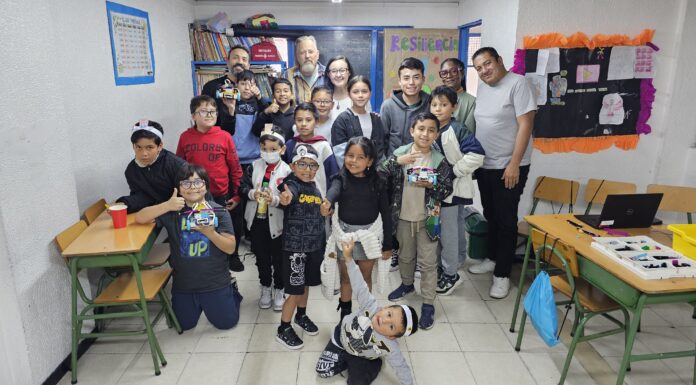 Mercer On Mission program an ‘invaluable’ experience for Mercerians, Colombians A group of children and adults pose and smile in a classroom filled with desks, colorful posters, and bookshelves.