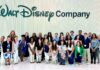 Senior gains media experience, connections during NYC internship A large group of people pose and smile in front of a wall with the Walt Disney Company logo.