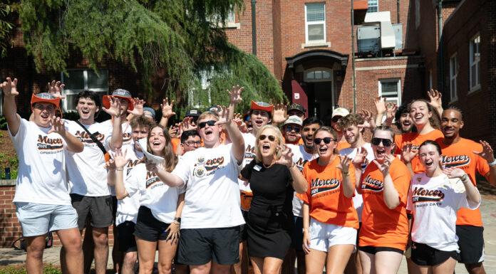 Mercer to welcome Class of 2029 for Opening Days A group of students and an adult stand outside, smiling and making paw gestures in matching Mercer shirts.