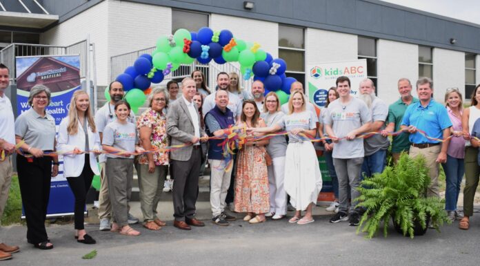 Kids Alliance for Better Care celebrates Evans Memorial Hospital’s emergency department as part of the Pediatric Emergency Care Project A group of people stand in front of a building holding a ribbon for a ribbon-cutting ceremony with balloons overhead.