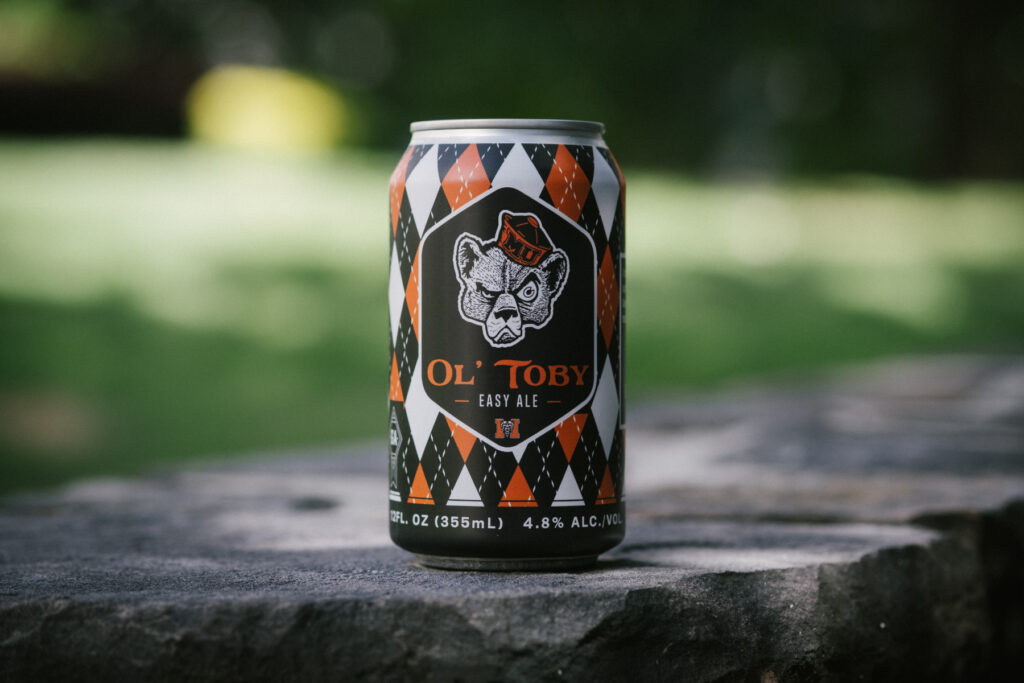 A can of Ol’ Toby Easy Ale sits on a stone surface with a blurred green background.