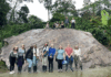 Mercerians help preserve environmental knowledge in the Amazon A group of people pose in front of and on top of a large rock in a lush, green outdoor setting.