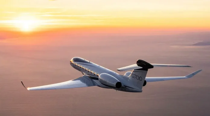 Georgia aerospace firms launch Georgia Aerospace & Defense Alliance Private jet labeled G700 flying over the ocean at sunset with orange and yellow sky in the background.