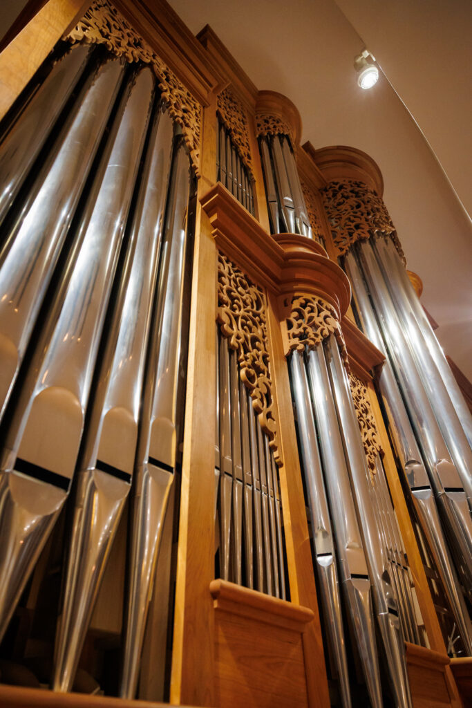 Close-up view of large organ pipes with ornate wooden framing in a church or concert hall.