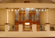 Handcrafted organ brings ‘new dimension’ to Mercer’s music programs A large pipe organ with ornate woodwork is displayed behind a railing in a well-lit concert hall.