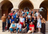 Mercer alumnus visits Auschwitz as part of education fellowship A large group of adults poses together on outdoor steps in front of an arched stone building.