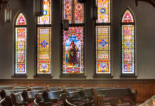 Mercer team researches how to enhance church worship for neurodivergent children Interior of Mercer University's Newton Chapel with wooden pews and large stained glass windows featuring Jesus.