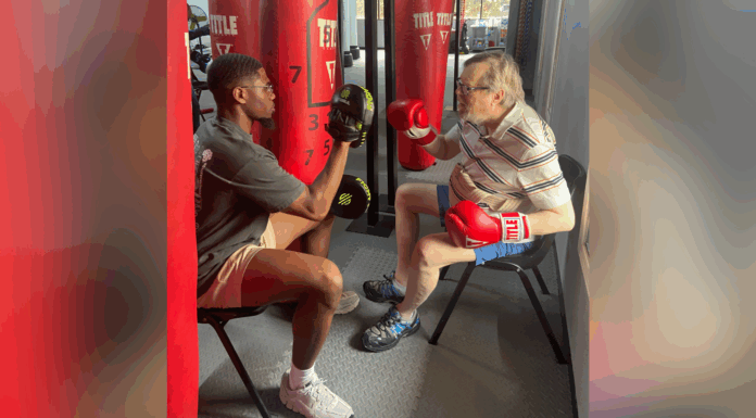 Physical therapy students bring compassion, positivity to service work An older man wearing boxing gloves practices punches with a trainer holding pads in a gym.