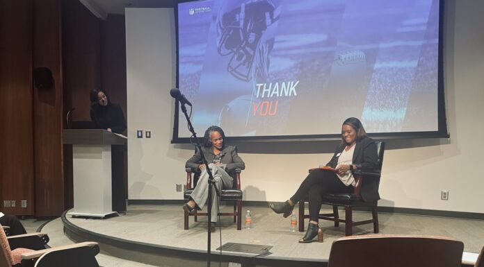 Speaker series looks at mental health care in sports Three women participate in a discussion on stage in an auditorium, with a Thank You slide projected behind them.