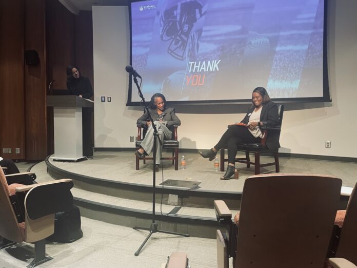 Three women participate in a discussion on stage in an auditorium, with a Thank You slide projected behind them.