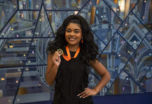 Mercer program helps freshmen grow as leaders on campus Georgia Taylor smiles while holding a medal on an orange ribbon in front of a geometric background.