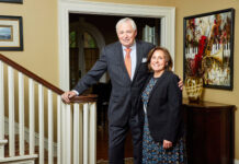 President Underwood leads Mercer for nearly 20 transformative years President William D. Underwood and wife Lesli Underwood stand together beside a staircase in a well-decorated home interior.