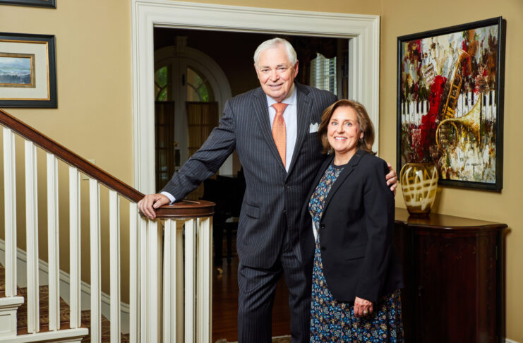 President William D. Underwood and wife Lesli Underwood stand together beside a staircase in a well-decorated home interior.