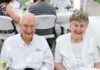 Tom McDonald leaves legacy of generosity, education initiatives at Mercer An elderly man and woman sit side by side at an outdoor table, both smiling at the camera.