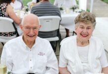 Tom McDonald leaves legacy of generosity, education initiatives at Mercer An elderly man and woman sit side by side at an outdoor table, both smiling at the camera.