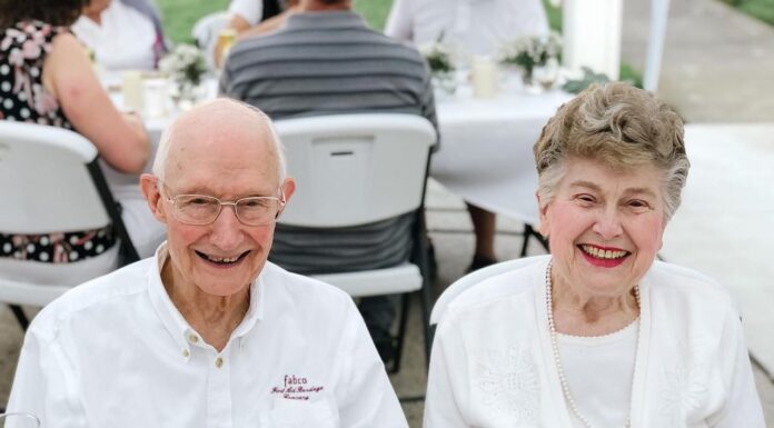 Tom McDonald leaves legacy of generosity, education initiatives at Mercer An elderly man and woman sit side by side at an outdoor table, both smiling at the camera.