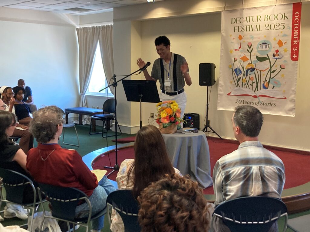 A person speaks at a podium to an audience during the Decatur Book Festival 2025, with a banner in the background.