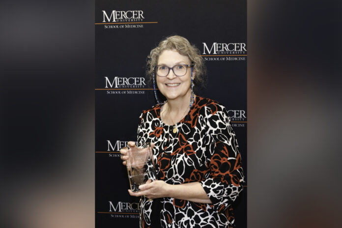 Donna Evans holding a glass award.