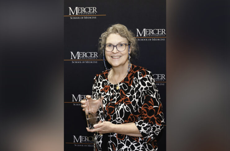 Donna Evans holding a glass award.
