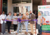 KidsABC celebrates Bleckley hospital’s emergency department for pediatric care Seven people stand behind a purple ribbon at an outdoor event in front of a building, with a kids ABC banner displayed.