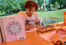Princeton Review names Mercer to 2026 Mental Health Services Honor Roll A man sits at an outdoor table coloring a mandala design with colored pencils beside a basket of art supplies.