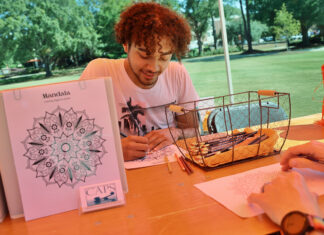 Princeton Review names Mercer to 2026 Mental Health Services Honor Roll A man sits at an outdoor table coloring a mandala design with colored pencils beside a basket of art supplies.