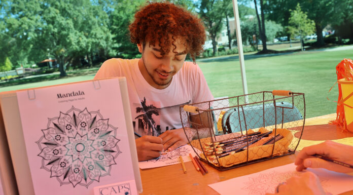 Princeton Review names Mercer to 2026 Mental Health Services Honor Roll A man sits at an outdoor table coloring a mandala design with colored pencils beside a basket of art supplies.