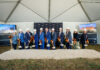 Mercer breaks ground on new medical school building in downtown Macon Eleven people in hard hats hold shovels at a groundbreaking ceremony under a tent with two display screens and a sand pile.